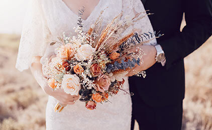 Der Bildausschnitt zeigt einen Brautstrauß, den ein Hochzeitspaar in der Hand hält.